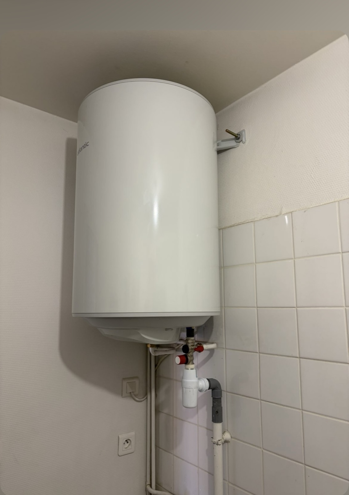 Chauffe-eau vertical fixé au mur d’une salle d’eau