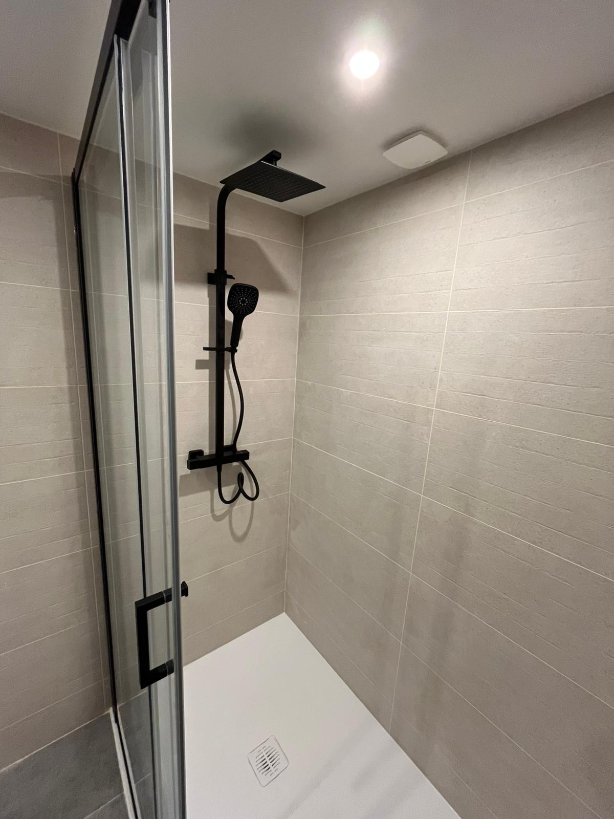 Douche avec colonne de douche noire et paroi coulissante
