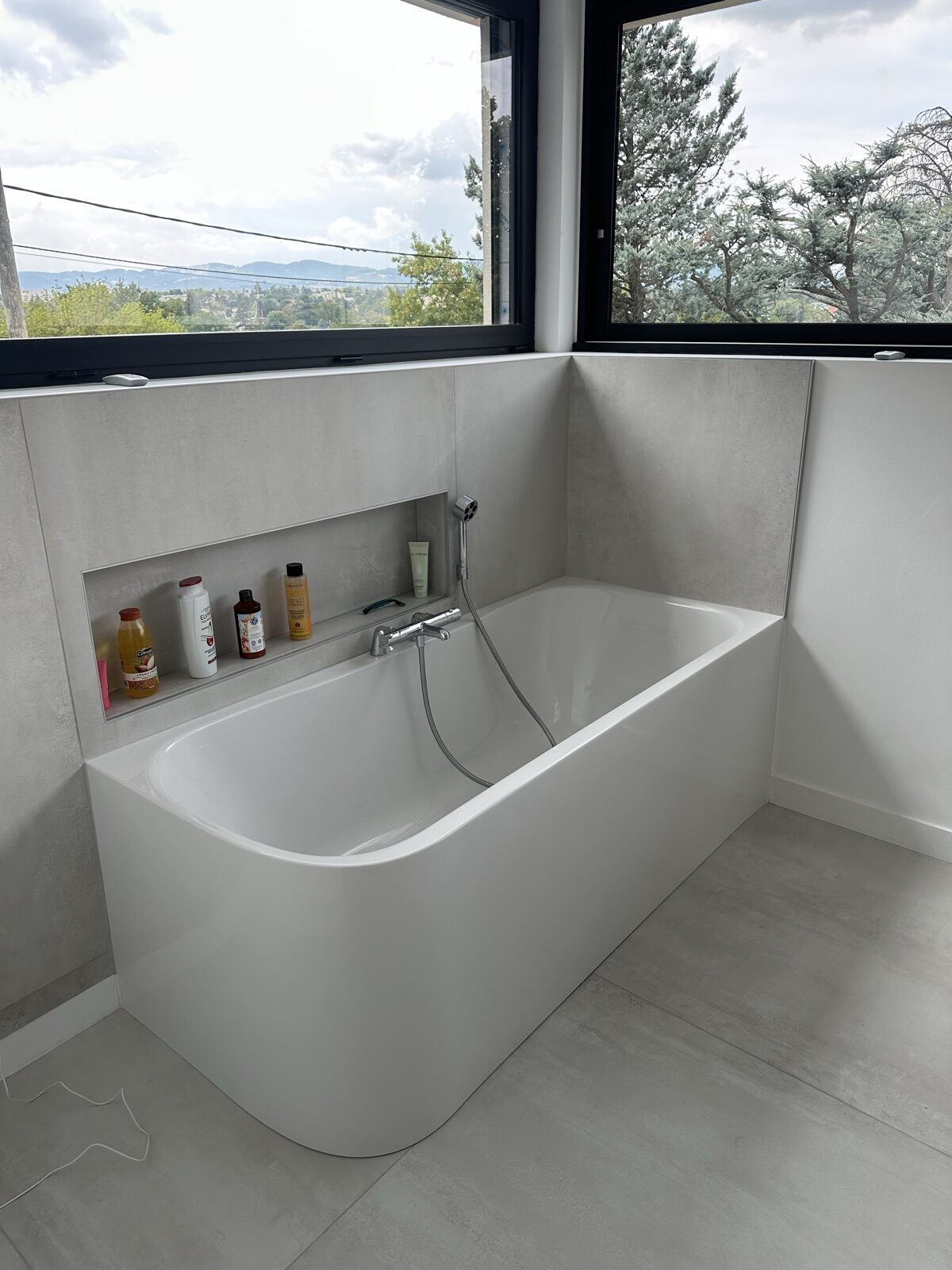 Baignoire posée sous une fenêtre, avec niche carrelée