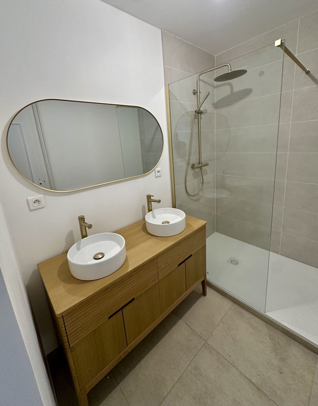 Salle de bain rénovée avec meuble double vasque en bois et douche vitrée