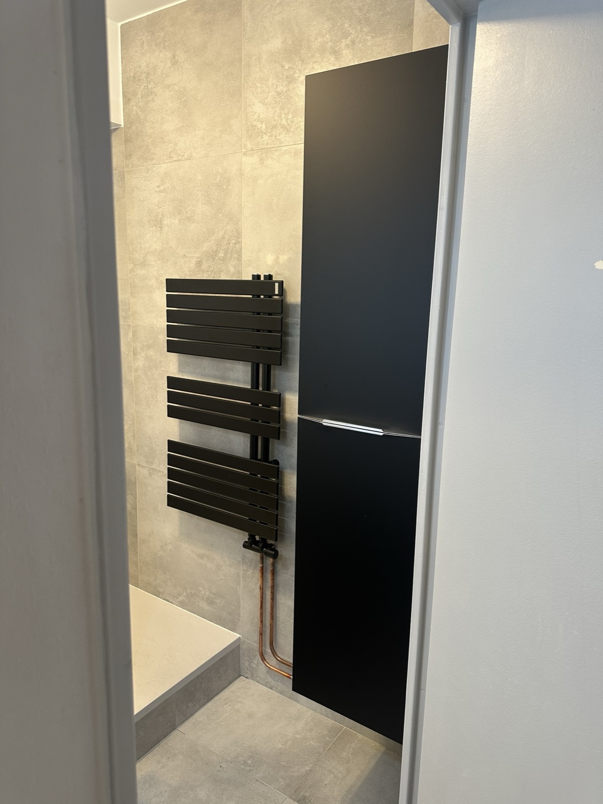 Sèche-serviettes noir raccordé dans une salle de bain